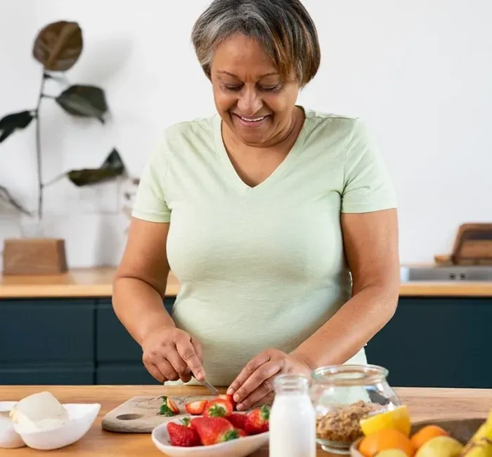 A woman preparing fruit and vegetables at a kitchen counter