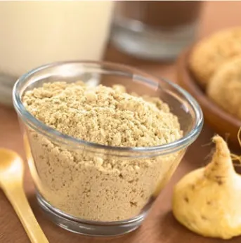Maca powder in a bowl next to whole maca roots